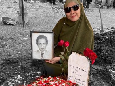 Makam Ayah. di mana anaknya yang sudah dewasa membawa foto sang ayah